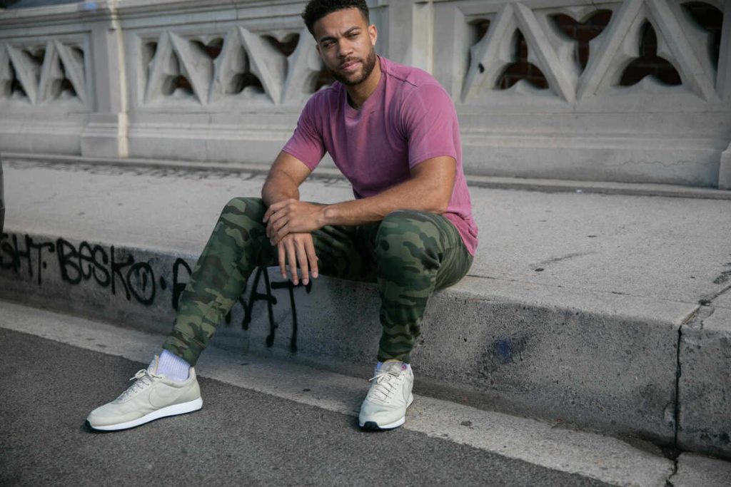 a man in a pink shirt is sitting on the sidewalk