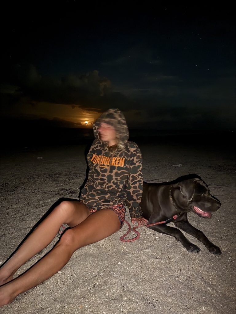 Custom Independent Trading Co Duck Camo Heavyweight Hoodie (IND4000) with orange Turducken print by Chef Threads, made with Apliiq, on a beach at night